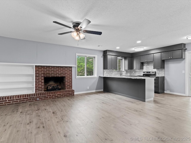 kitchen featuring stainless steel electric range, ceiling fan, a textured ceiling, a peninsula, and open floor plan