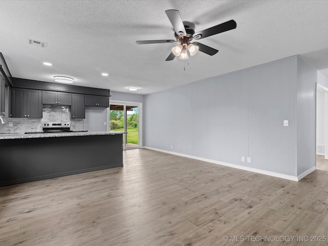 unfurnished living room with a sink, light wood finished floors, a textured ceiling, a ceiling fan, and visible vents