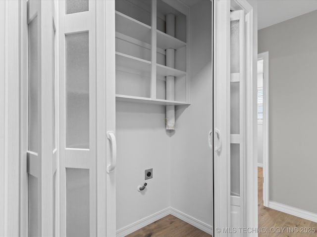 laundry room featuring electric dryer hookup, baseboards, and wood finished floors