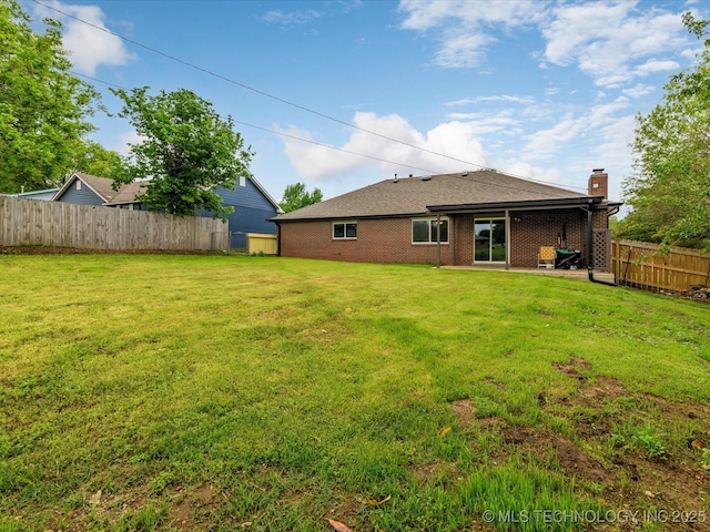rear view of property featuring brick siding, a fenced backyard, and a yard