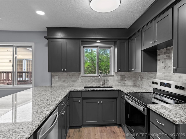 kitchen featuring a sink, appliances with stainless steel finishes, backsplash, and light stone counters
