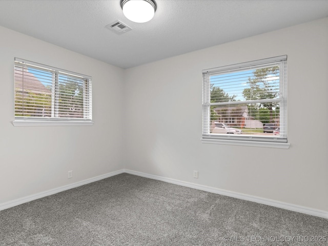 unfurnished room with baseboards, carpet flooring, a textured ceiling, and visible vents