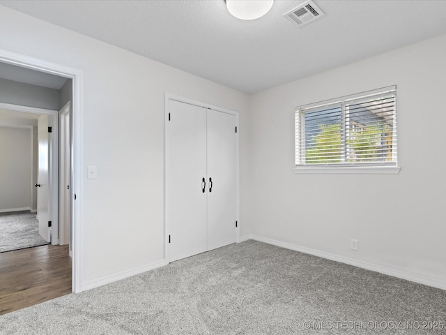 unfurnished bedroom with carpet floors, baseboards, visible vents, and a closet