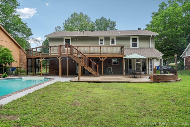 rear view of house with a lawn, stairs, a deck, and an outdoor pool