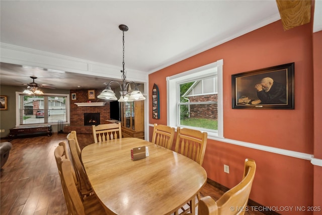dining room with crown molding, wood finished floors, a wealth of natural light, and a fireplace