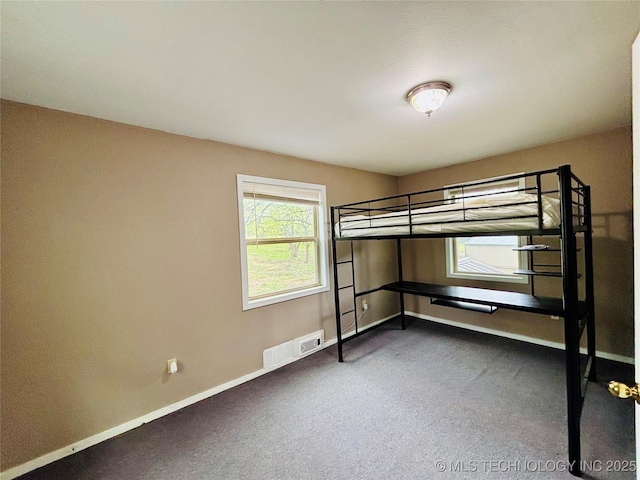 unfurnished bedroom featuring baseboards, carpet floors, and visible vents
