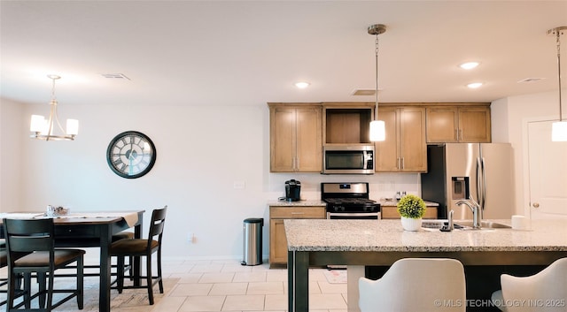 kitchen featuring stainless steel appliances, decorative light fixtures, visible vents, and a sink