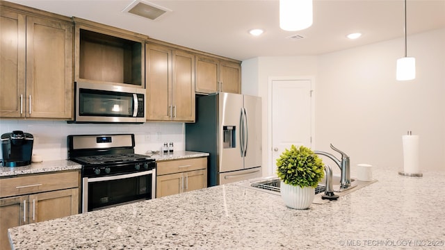 kitchen with decorative backsplash, visible vents, light stone countertops, a sink, and stainless steel appliances