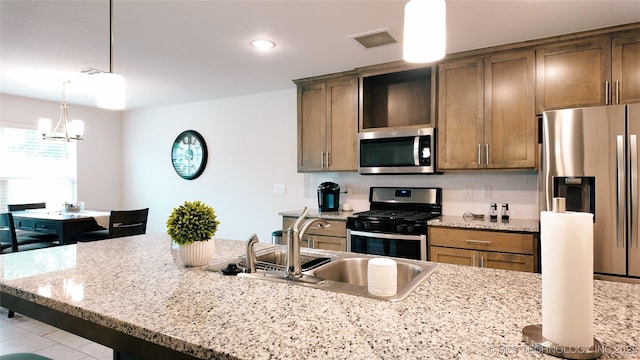 kitchen with visible vents, a breakfast bar area, a sink, hanging light fixtures, and stainless steel appliances
