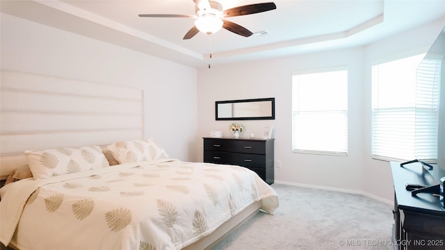 bedroom featuring visible vents, baseboards, ceiling fan, light colored carpet, and a raised ceiling