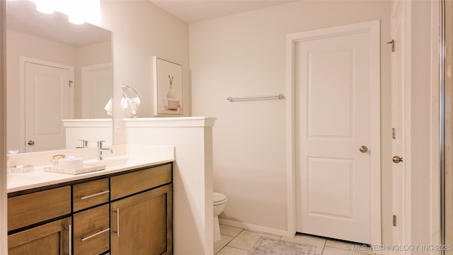 bathroom featuring double vanity, tile patterned flooring, a sink, baseboards, and toilet