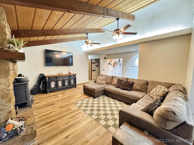 living room with ceiling fan, a wood stove, wood finished floors, wooden ceiling, and vaulted ceiling with beams