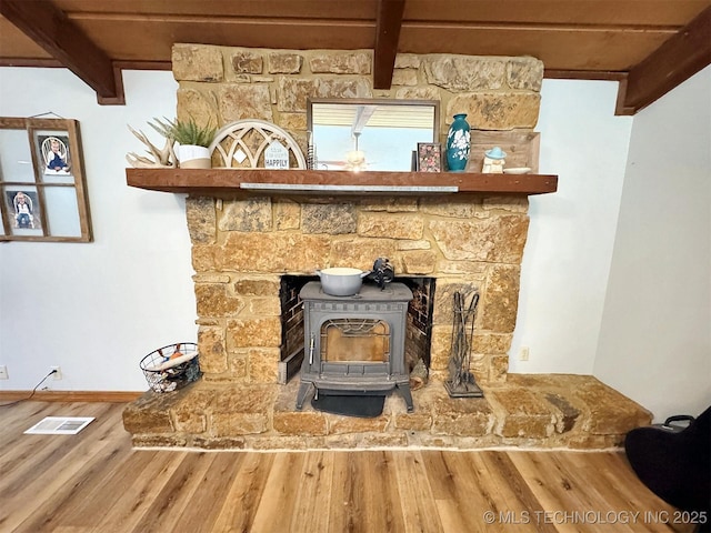 room details with baseboards, visible vents, wood finished floors, and a wood stove