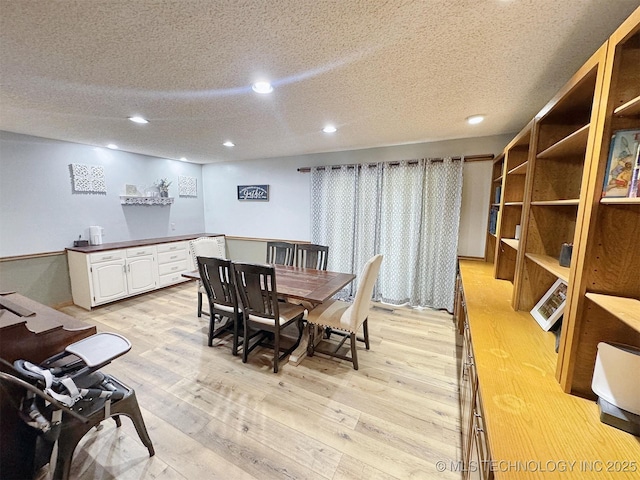 dining room with recessed lighting, a textured ceiling, and light wood finished floors