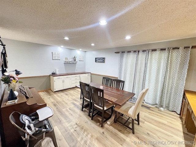 dining room featuring recessed lighting, light wood-type flooring, and a textured ceiling