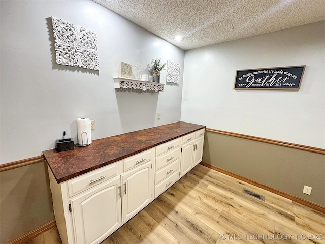 bar with visible vents, baseboards, recessed lighting, light wood-type flooring, and a textured ceiling