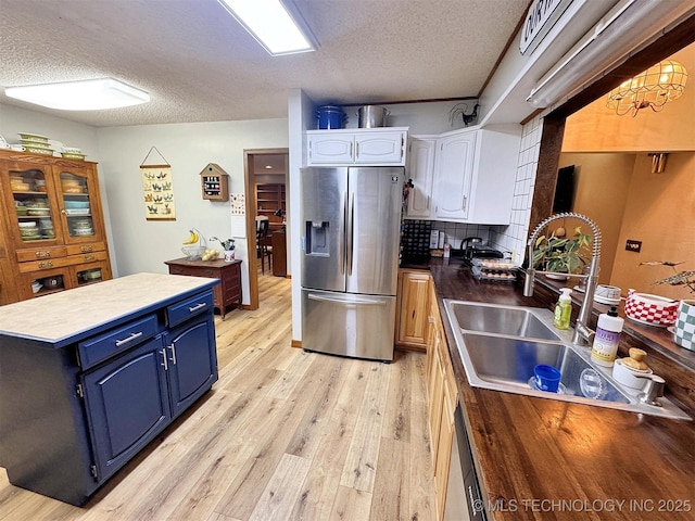 kitchen featuring stainless steel fridge with ice dispenser, blue cabinets, a textured ceiling, and white cabinetry