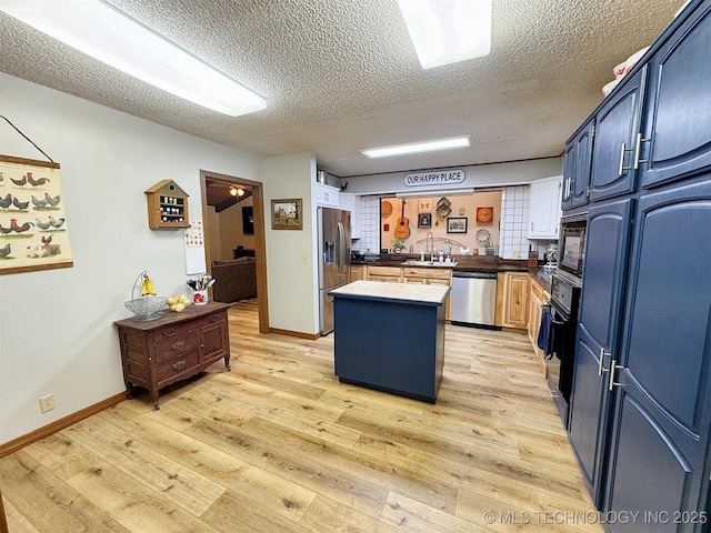 kitchen with light wood-style floors, built in appliances, a textured ceiling, blue cabinetry, and a kitchen island