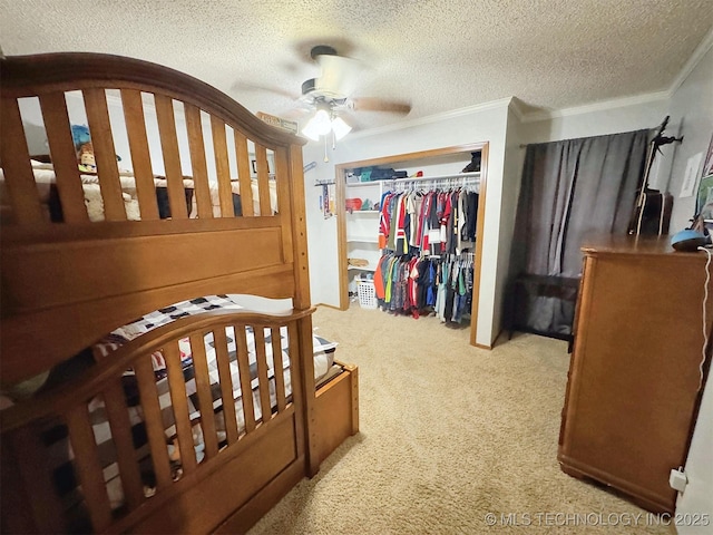 bedroom with ceiling fan, a textured ceiling, light colored carpet, crown molding, and a closet