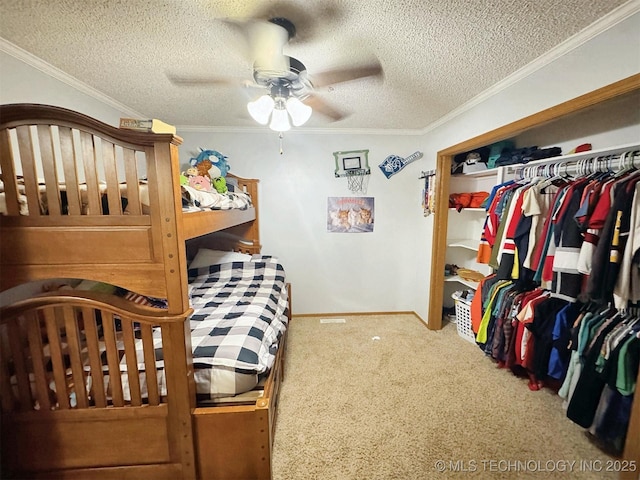 carpeted bedroom featuring a textured ceiling, a ceiling fan, baseboards, ornamental molding, and a closet