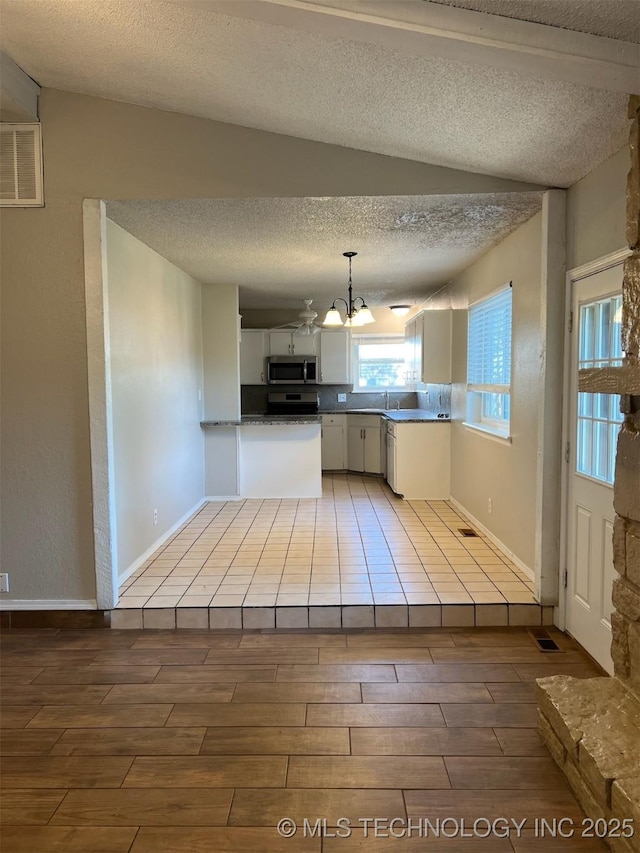 1209 S 29th St, Broken Arrow, OK 74014 - kitchen featuring wood tiled floor, a textured ceiling, dark countertops, stainless steel microwave, and a notable chandelier