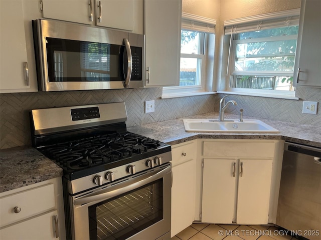 1209 S 29th St, Broken Arrow, OK 74014 - kitchen featuring light tile patterned floors, white cabinets, a sink, appliances with stainless steel finishes, and backsplash