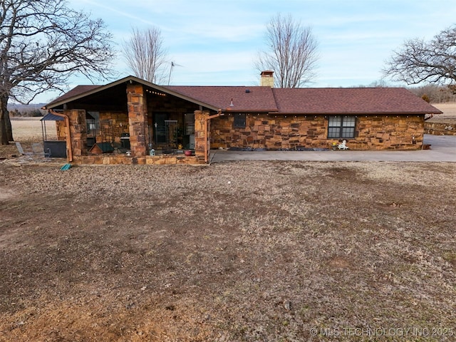 back of property with a chimney and stone siding