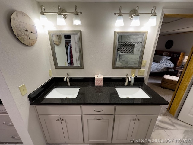 full bath featuring a sink, double vanity, and connected bathroom