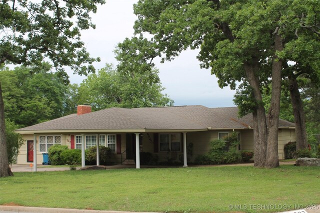 single story home with a shingled roof, a front lawn, and a chimney