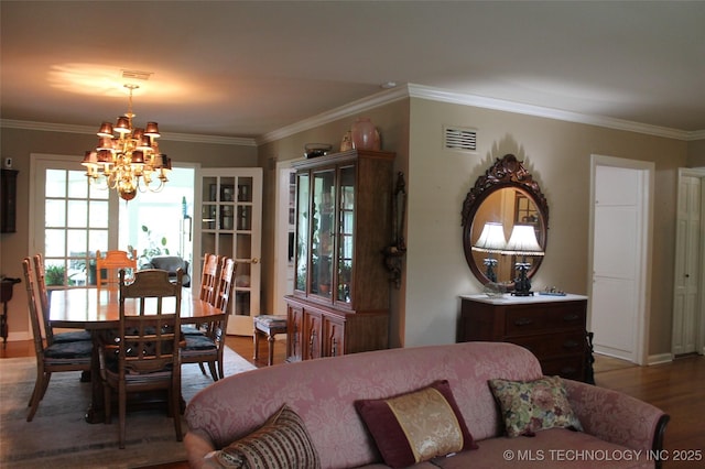 interior space with a notable chandelier, baseboards, wood finished floors, visible vents, and ornamental molding