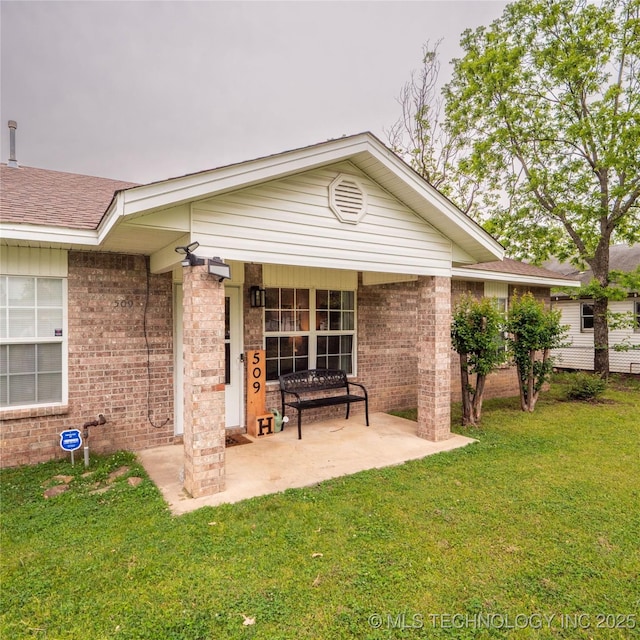 back of property with a lawn, brick siding, and a patio