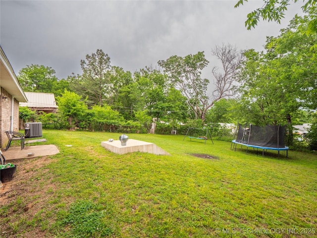 view of yard with a trampoline and central AC