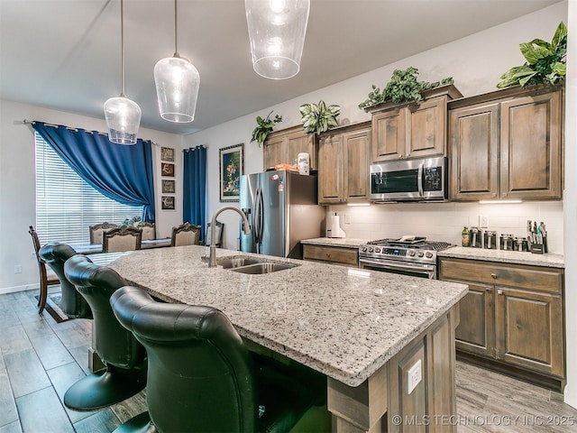 6342 E 148th St S, Bixby, OK 74008 - kitchen featuring appliances with stainless steel finishes, a sink, a center island with sink, light stone countertops, and tasteful backsplash