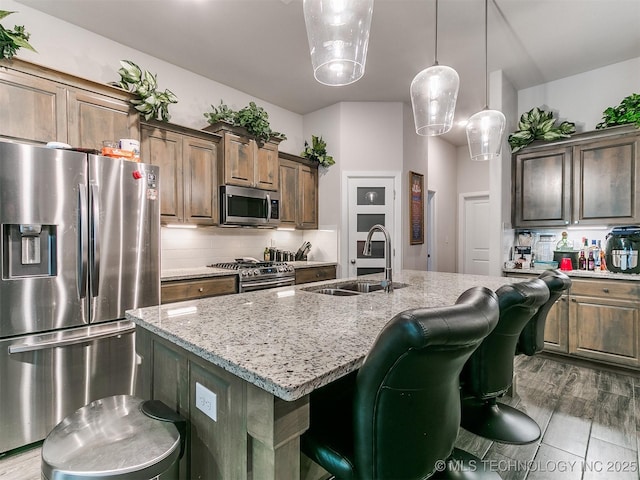 6342 E 148th St S, Bixby, OK 74008 - kitchen with stainless steel appliances, a sink, light stone counters, an island with sink, and a kitchen breakfast bar