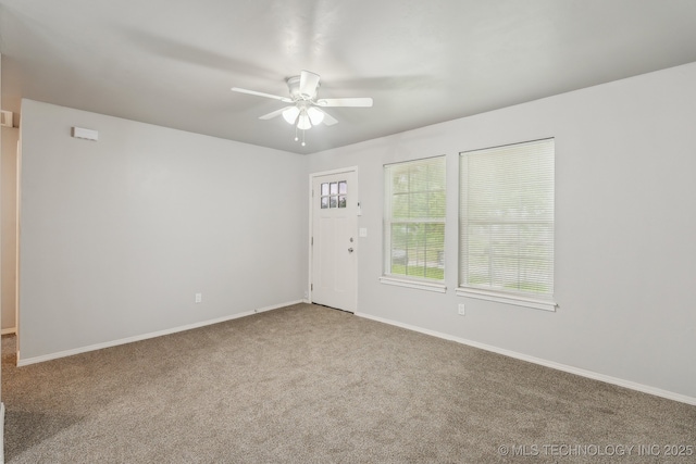 unfurnished room with carpet floors, a ceiling fan, and baseboards