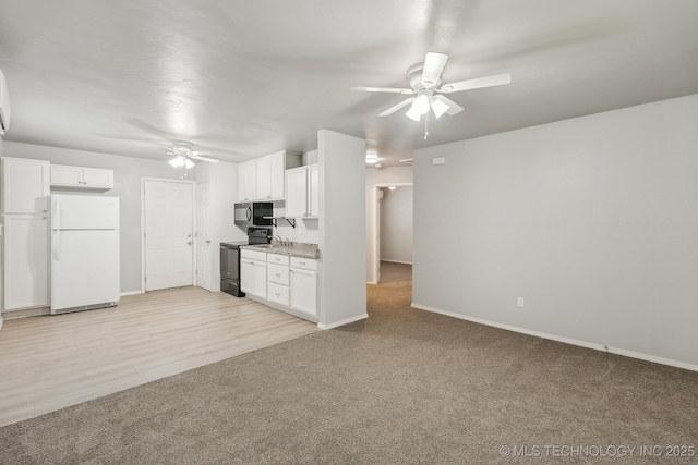 kitchen featuring a ceiling fan, light colored carpet, baseboards, black appliances, and white cabinetry