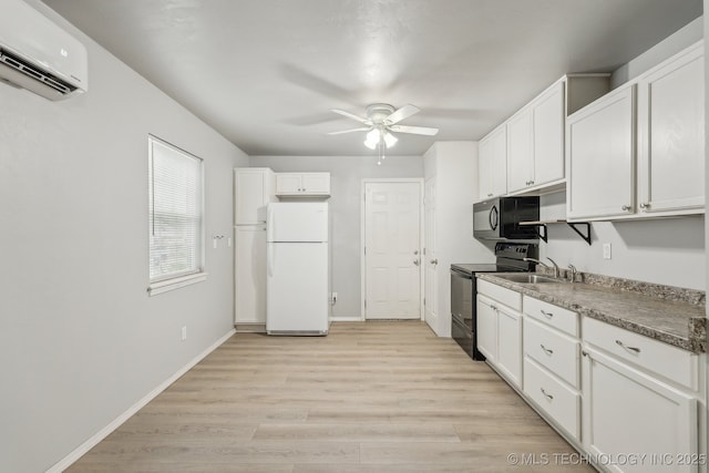 kitchen with a ceiling fan, a wall mounted AC, light wood-type flooring, black appliances, and white cabinetry