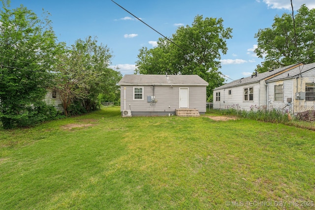 rear view of house featuring fence and a yard