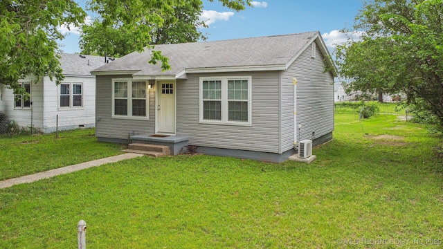view of front facade featuring roof with shingles, central air condition unit, a front yard, and fence