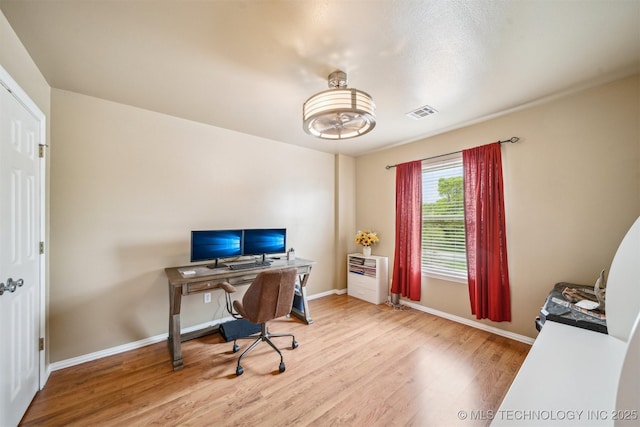 home office with baseboards, wood finished floors, and visible vents