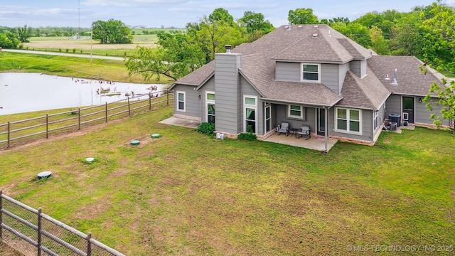 rear view of property featuring a patio, a fenced backyard, roof with shingles, a chimney, and a water view