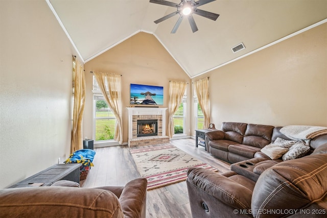 living area featuring ceiling fan, a fireplace, wood finished floors, vaulted ceiling, and visible vents