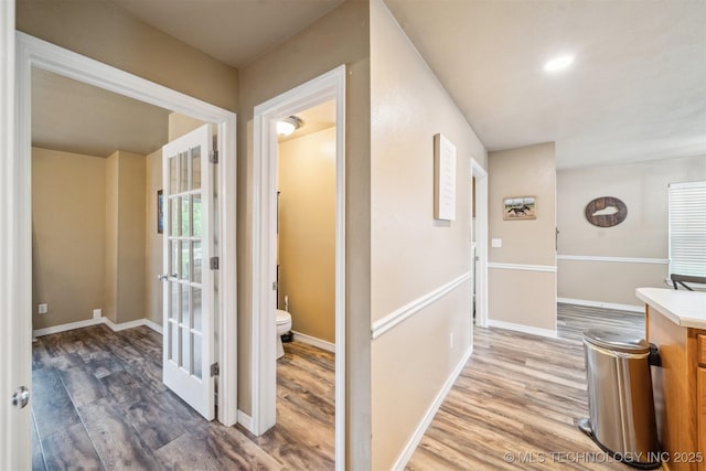 hall featuring light wood-type flooring and baseboards