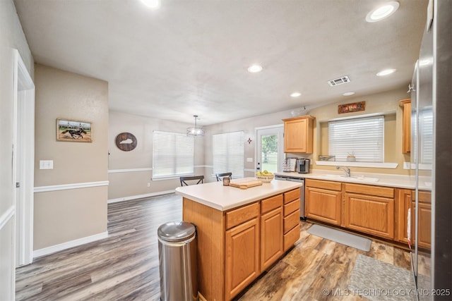 kitchen with stainless steel dishwasher, visible vents, a center island, light countertops, and light wood-type flooring