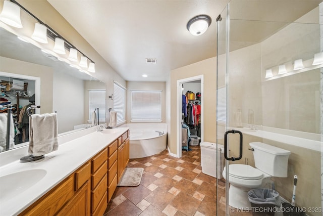full bath featuring double vanity, visible vents, a sink, and a garden tub