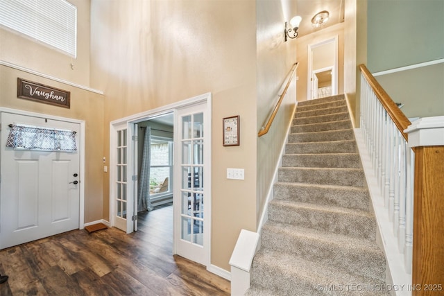 foyer featuring baseboards, a high ceiling, stairs, and wood finished floors