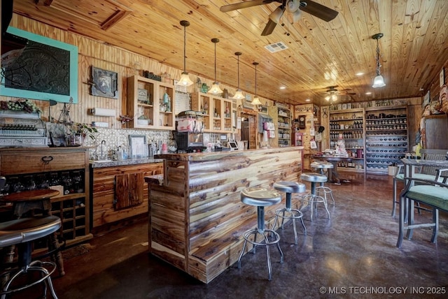 bar with a ceiling fan, concrete flooring, a bar, and wood ceiling
