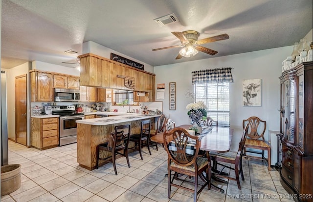 interior space featuring ceiling fan, visible vents, light countertops, a peninsula, and stainless steel appliances