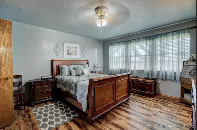 bedroom featuring a textured ceiling, a ceiling fan, and wood finished floors