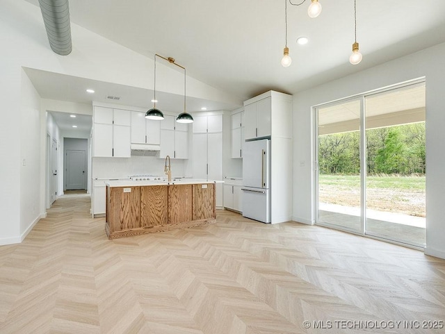 kitchen featuring a sink, light countertops, white cabinets, white refrigerator, and vaulted ceiling
